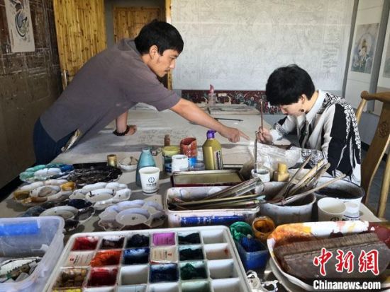 圖為2020年8月下旬，敦煌“80后”畫家張杰龍(左)在為云南麗江“學(xué)生”莫北講解敦煌壁畫的繪畫技巧?！●T志軍 攝