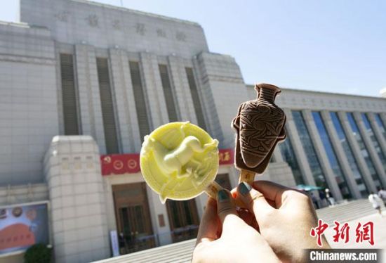 2021年7月30日，游客手拿“銅奔馬”“彩陶瓶”造型的雪糕，在甘肅省博物館前拍照打卡?！「哒?攝