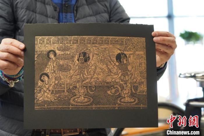 圖為手工書藝人展示敦煌雕版壁畫印刷品。　九美旦增 　攝