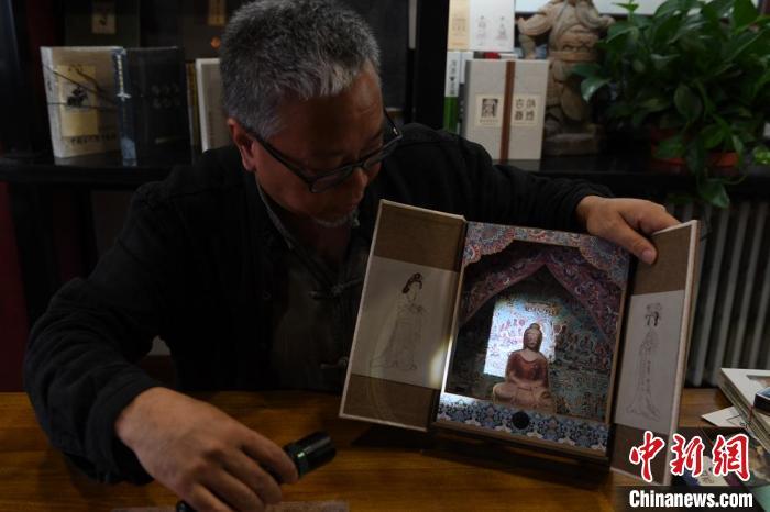 圖為讀者出版集團(tuán)讀者晉林工作室獨(dú)立出品人徐晉林，展示互動(dòng)性強(qiáng)的敦煌題材手工書。(資料圖) 楊艷敏 攝