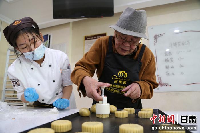 當日，受邀參加活動的臺胞臺屬代表、兩岸婚姻及子女、在甘臺商代表等歡聚一堂。圖為77歲的在甘臺胞潘天鑒制作月餅。九美旦增 攝
