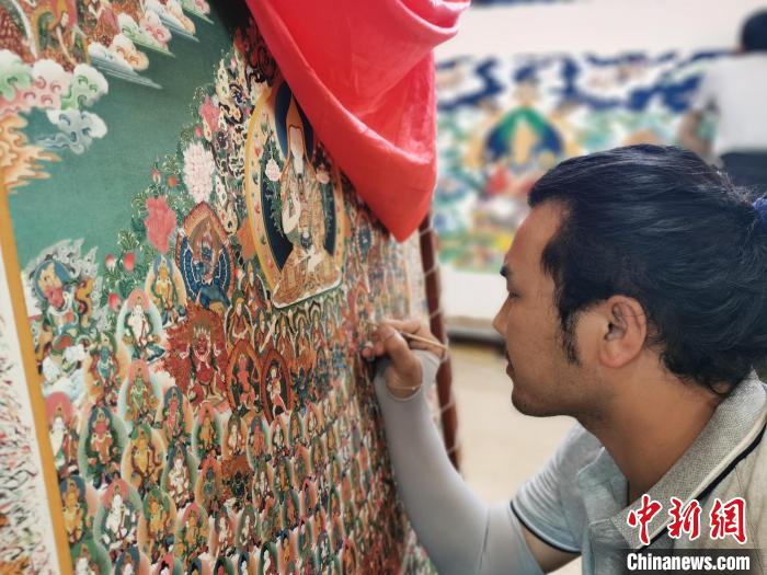 圖為更登才讓的徒弟繪畫唐卡?！?zhí)砀?攝
