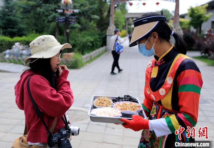 圖為身穿土族服飾的女性介紹當(dāng)?shù)靥厣〕??！⊙Φ?攝