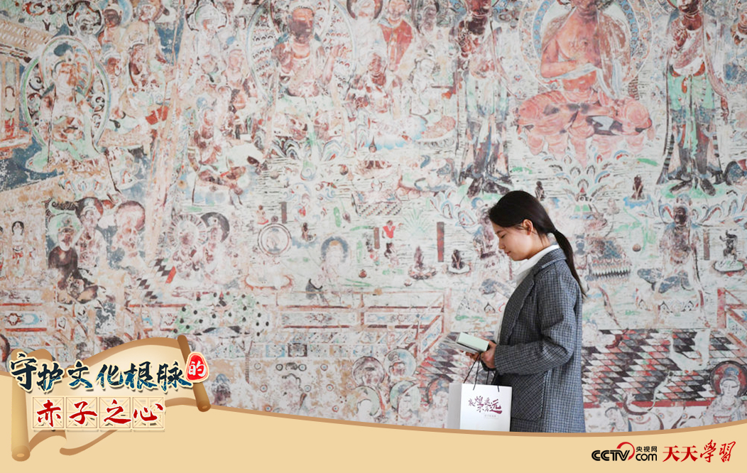 2023年4月25日，敦煌研究院文物數(shù)字化保護團隊創(chuàng)意營銷人員廖雪婷從一幅高保真復(fù)制壁畫前走過。