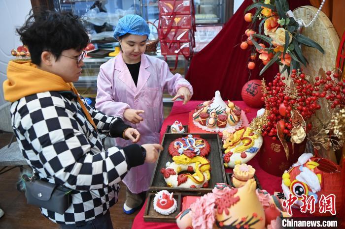 1月25日，隨著春節(jié)臨近，蘭州一花饃店“龍”元素花饃熱銷。圖為工作人員向顧客推薦“龍”元素花饃。九美旦增 攝</p><p>