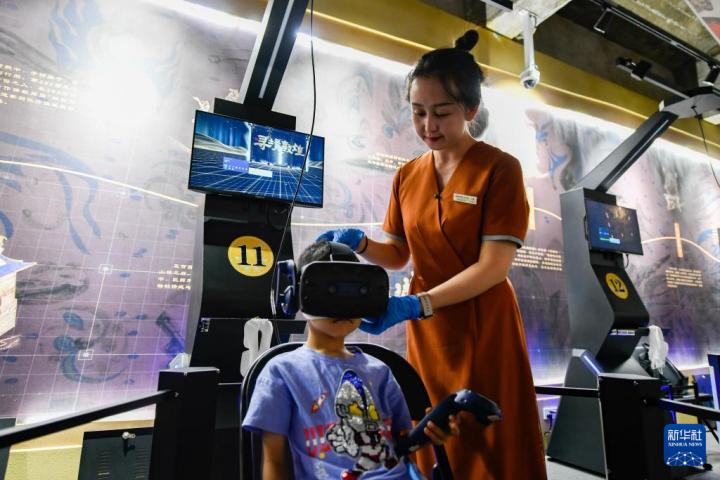7月22日，敦煌研究院文化弘揚部工作人員引導游客佩戴使用VR設備。新華社記者 郎兵兵 攝</p>
<p>