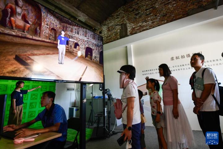 7月22日，游客體驗“尋境敦煌——數(shù)字敦煌沉浸展”后，在虛擬演播廳拍攝一段真人與洞窟虛擬場景交互的視頻。新華社記者 郎兵兵 攝</p>
<p>