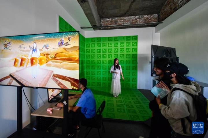 7月22日，游客體驗“尋境敦煌——數(shù)字敦煌沉浸展”后，在虛擬演播廳拍攝一段真人與洞窟虛擬場景交互的視頻。新華社記者 郎兵兵 攝</p>
<p>